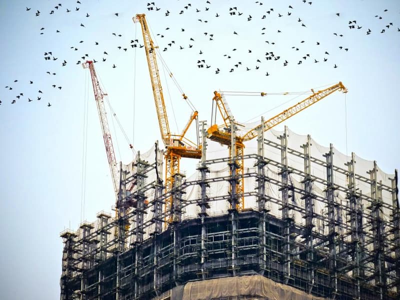 Edificio en construcción con grúas, fase de ejecución de un proyecto acústico en Barcelona