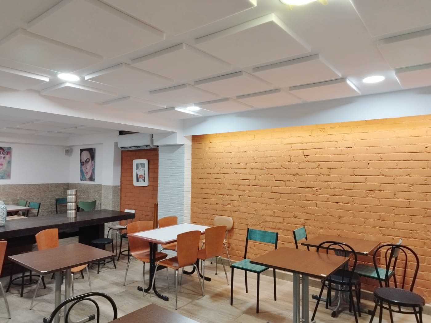 Tratamientos fonoabsorbentes para la reverberación Comedor de restaurante con paneles fonoabsorbentes suspendidos del techo para bajar la reverberación